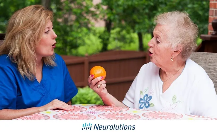 nurse helping elderly patient speak while holding an orange