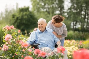 Home caregiver and senior man on a wheelchair, walking outdoors